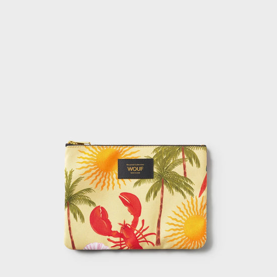 Neceser plano con estampado tropical de aves y flores exóticas sobre fondo oscuro, con cierre de cremallera dorada y etiqueta de cuero reciclado de Wouf.