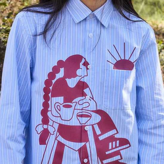 Camisa de rayas con corte boxy y un estampado artístico integral en tonos cálidos inspirado en el atardecer, fruto de la colaboración entre NWHR y Pruden.