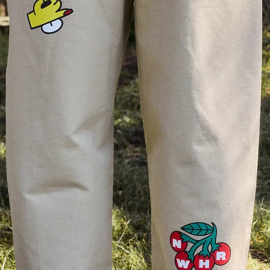 Pantalón tipo chino de color beige con corte relajado, dos pinzas en la parte frontal y cierre de doble botón, fabricado en algodón orgánico por NWHR.