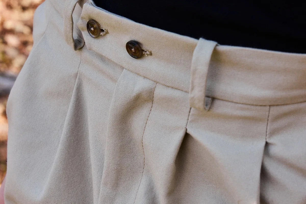 Pantalón tipo chino de color beige con corte relajado, dos pinzas en la parte frontal y cierre de doble botón, fabricado en algodón orgánico por NWHR.