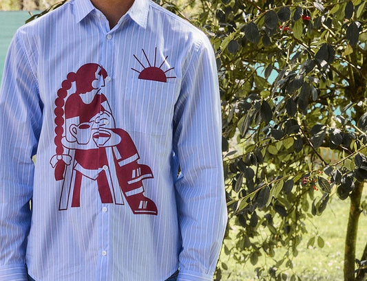 Camisa de manga corta con corte boxy y un estampado artístico integral en tonos cálidos inspirado en el atardecer, fruto de la colaboración entre NWHR y Pruden.