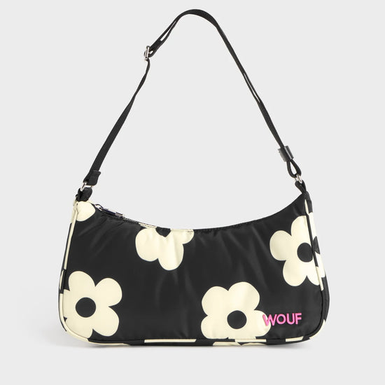 Bolso de hombro con estampado de margaritas blancas sobre fondo oscuro, logo metálico frontal, cremallera superior y correa ajustable, modelo Night Daisy de Wouf.