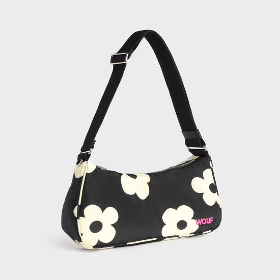 Bolso de hombro con estampado de margaritas blancas sobre fondo oscuro, logo metálico frontal, cremallera superior y correa ajustable, modelo Night Daisy de Wouf.