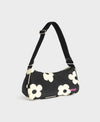 Bolso de hombro con estampado de margaritas blancas sobre fondo oscuro, logo metálico frontal, cremallera superior y correa ajustable, modelo Night Daisy de Wouf.