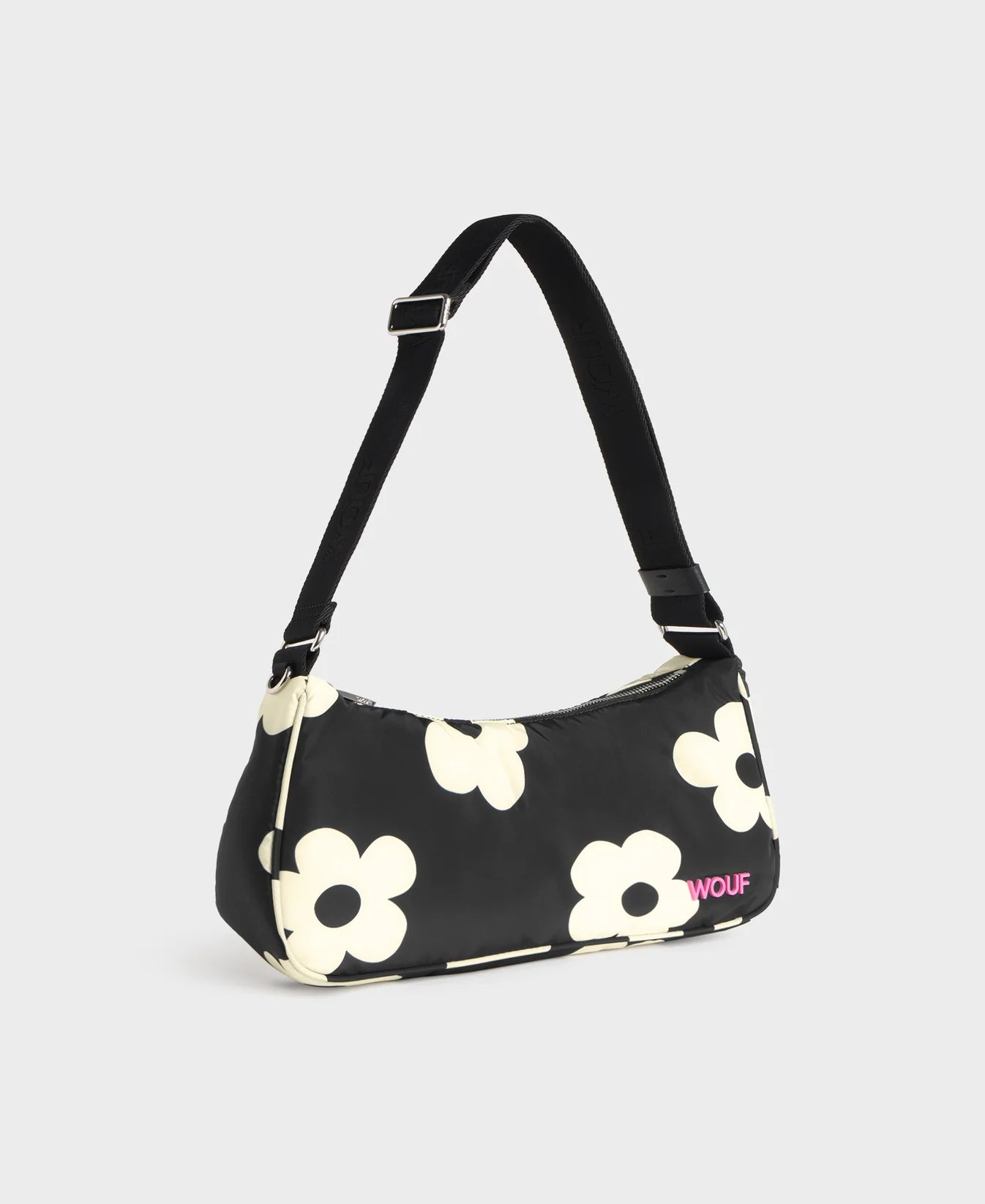 Bolso de hombro con estampado de margaritas blancas sobre fondo oscuro, logo metálico frontal, cremallera superior y correa ajustable, modelo Night Daisy de Wouf.