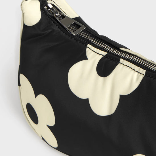 Bolso de hombro con estampado de margaritas blancas sobre fondo oscuro, logo metálico frontal, cremallera superior y correa ajustable, modelo Night Daisy de Wouf.