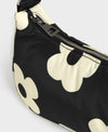 Bolso de hombro con estampado de margaritas blancas sobre fondo oscuro, logo metálico frontal, cremallera superior y correa ajustable, modelo Night Daisy de Wouf.