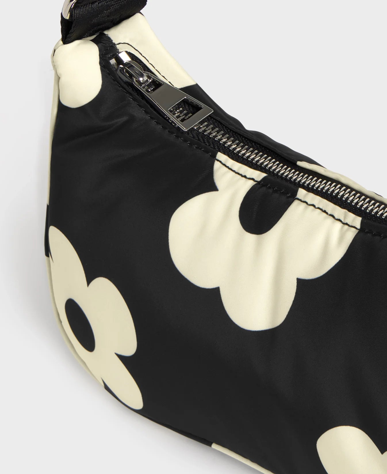 Bolso de hombro con estampado de margaritas blancas sobre fondo oscuro, logo metálico frontal, cremallera superior y correa ajustable, modelo Night Daisy de Wouf.