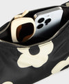Bolso de hombro con estampado de margaritas blancas sobre fondo oscuro, logo metálico frontal, cremallera superior y correa ajustable, modelo Night Daisy de Wouf.