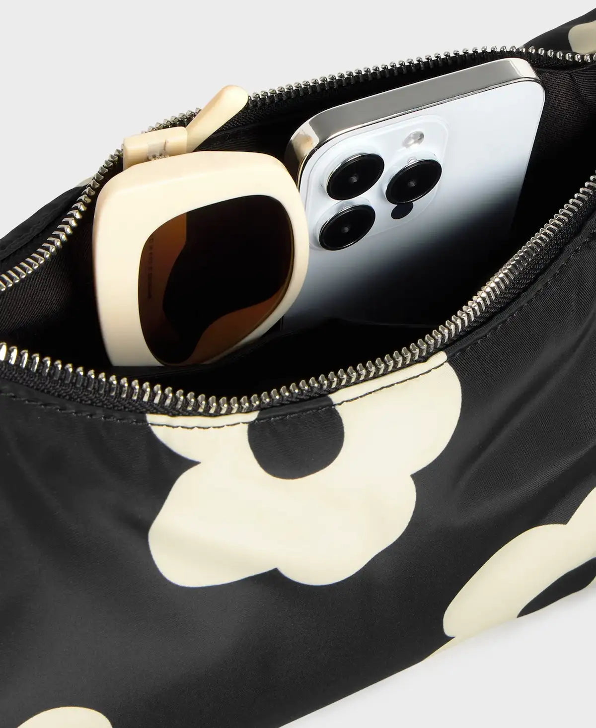 Bolso de hombro con estampado de margaritas blancas sobre fondo oscuro, logo metálico frontal, cremallera superior y correa ajustable, modelo Night Daisy de Wouf.