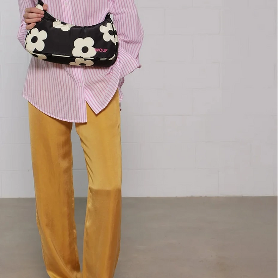 Bolso de hombro con estampado de margaritas blancas sobre fondo oscuro, logo metálico frontal, cremallera superior y correa ajustable, modelo Night Daisy de Wouf.