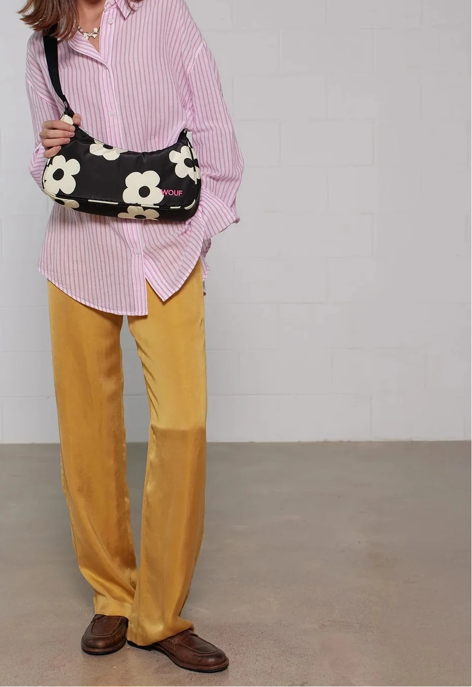 Bolso de hombro con estampado de margaritas blancas sobre fondo oscuro, logo metálico frontal, cremallera superior y correa ajustable, modelo Night Daisy de Wouf.