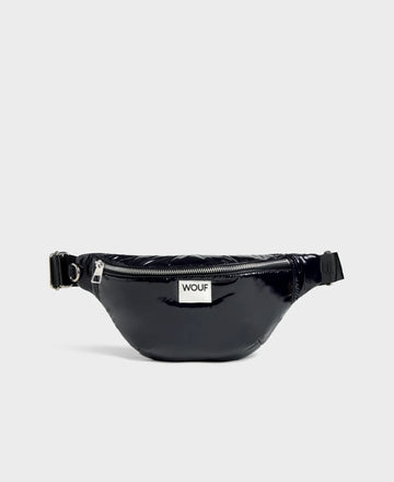 Riñonera negra con acabado brillante de la colección Nuit de Wouf, con correa ajustable, cremallera superior y etiqueta de cuero reciclado con logo frontal.