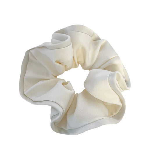 Coletero tipo scrunchie gigante de color blanco roto con capas de tela en forma de pétalos de flor anémona de la marca danesa By Stær.
