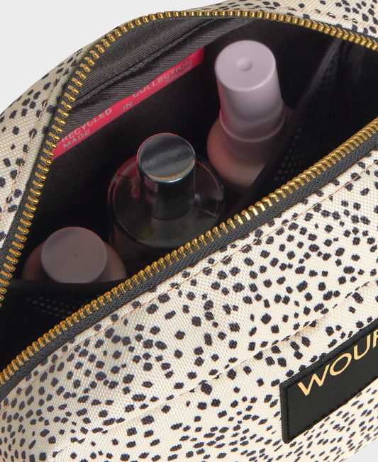 Neceser pequeño con acabado brillante en color crema suave, cierre de cremallera superior dorada y etiqueta de cuero reciclado con el logo de Wouf en el frontal.