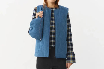 Chaleco reversible para mujer de algodón orgánico, con una cara en tejido denim azul con bolsillos y otra cara en color negro liso, de la marca Suite13.