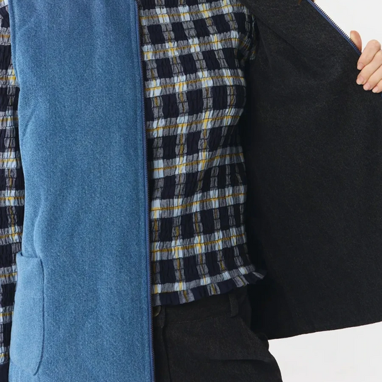 Chaleco reversible para mujer de algodón orgánico, con una cara en tejido denim azul con bolsillos y otra cara en color negro liso, de la marca Suite13.