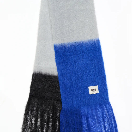 Bufanda de mohair con diseño de bloques de color en tonos contrastados, textura voluminosa de pelo suave y flecos largos hechos a mano en los extremos.