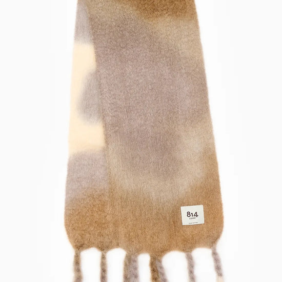 Bufanda de mohair y lana con estampado artesanal tie-dye en tonos degradados azules y naturales, con flecos largos hechos a mano en los extremos.