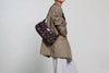 Bolso de hombro con estampado floral colorido sobre fondo oscuro, silueta suave y relajada, con correa ajustable negra y etiqueta de cuero reciclado de Wouf.
