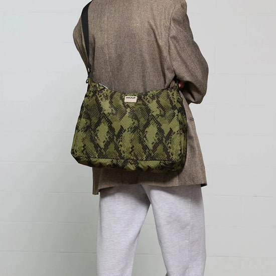 Bolso tipo hobo con estampado de piel de serpiente en tonos oscuros, con silueta curva, correa ajustable negra y detalle de etiqueta de cuero de Wouf.