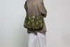 Bolso tipo hobo con estampado de piel de serpiente en tonos oscuros, con silueta curva, correa ajustable negra y detalle de etiqueta de cuero de Wouf.