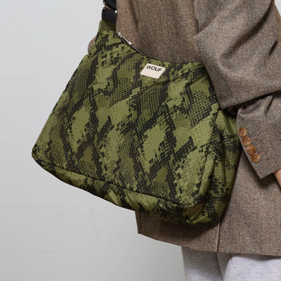 Bolso tipo hobo con estampado de piel de serpiente en tonos oscuros, con silueta curva, correa ajustable negra y detalle de etiqueta de cuero de Wouf.