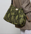 Bolso tipo hobo con estampado de piel de serpiente en tonos oscuros, con silueta curva, correa ajustable negra y detalle de etiqueta de cuero de Wouf.
