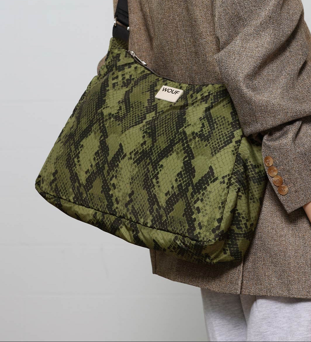 Bolso tipo hobo con estampado de piel de serpiente en tonos oscuros, con silueta curva, correa ajustable negra y detalle de etiqueta de cuero de Wouf.