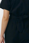 Mono largo de color negro con manga corta, cuello de camisa y pernera ancha, que incluye un cinturón a juego y botones naturales en la parte frontal.