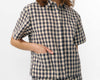 Camisa de manga corta con estampado de cuadros en tonos grises, cuello de solapa, dos bolsillos frontales cuadrados y cierre de botones naturales de corozo.