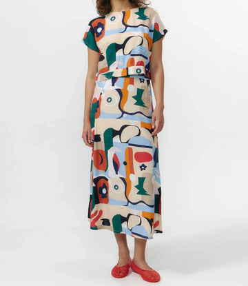 Falda midi de tejido fluido con estampado artístico de barcos y motivos marinos en azul sobre fondo crema, con una abertura lateral en el bajo.
