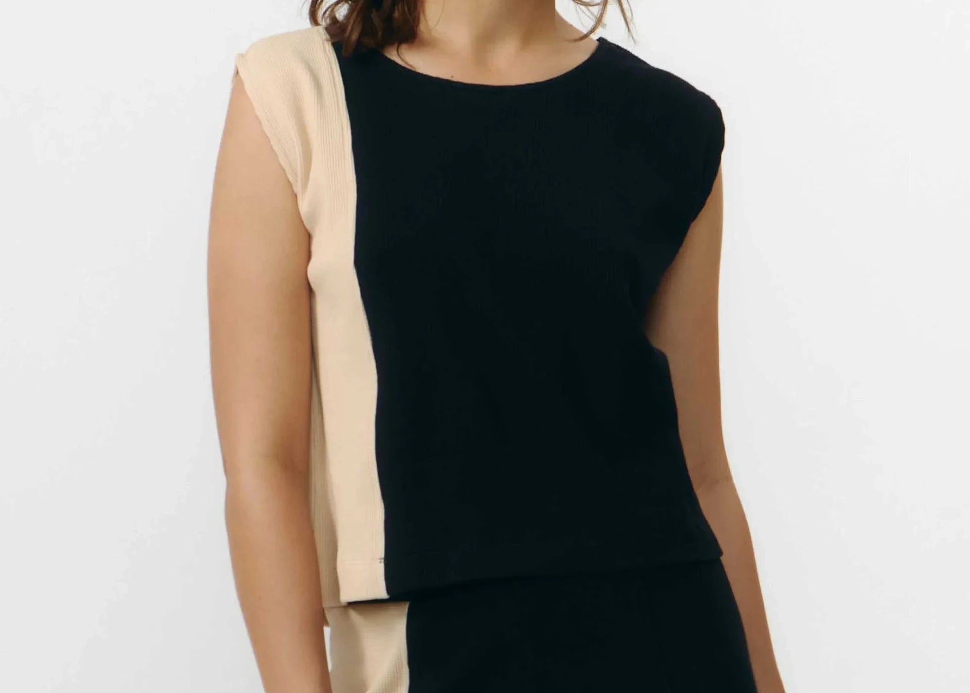 Top ajustado sin mangas en color negro con textura de punto waffle, cuello redondo y detalle de cierre trasero con un pequeño botón de madera natural.