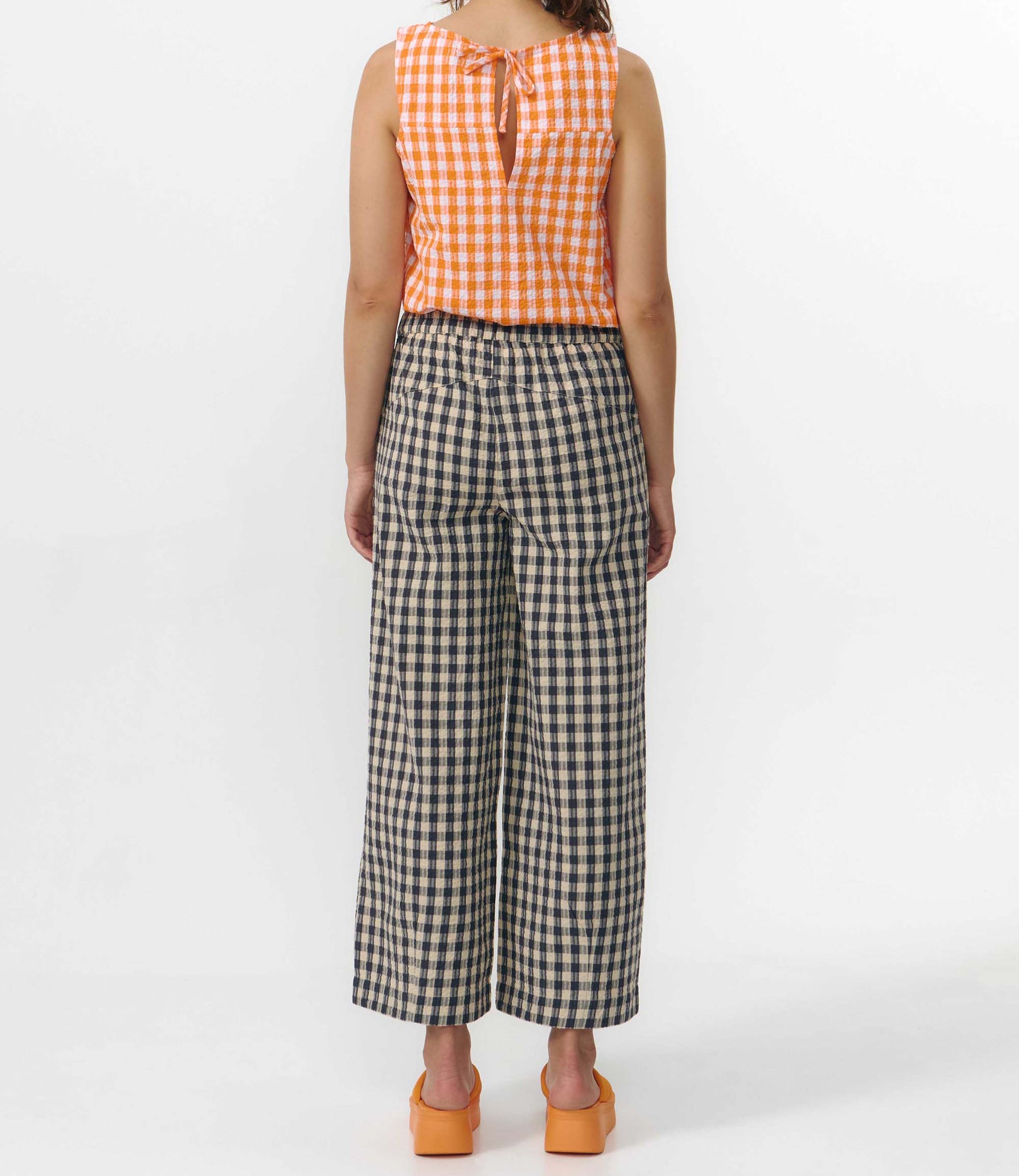 Pantalón culotte de pernera ancha con estampado de cuadros en tonos grises y blancos, talle alto con cintura elástica y bolsillos laterales, hecho en algodón orgánico.