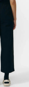 Pantalón de corte culotte en color negro con pernera ancha y corta, talle alto con cintura elástica y bolsillos laterales, fabricado en algodón orgánico.