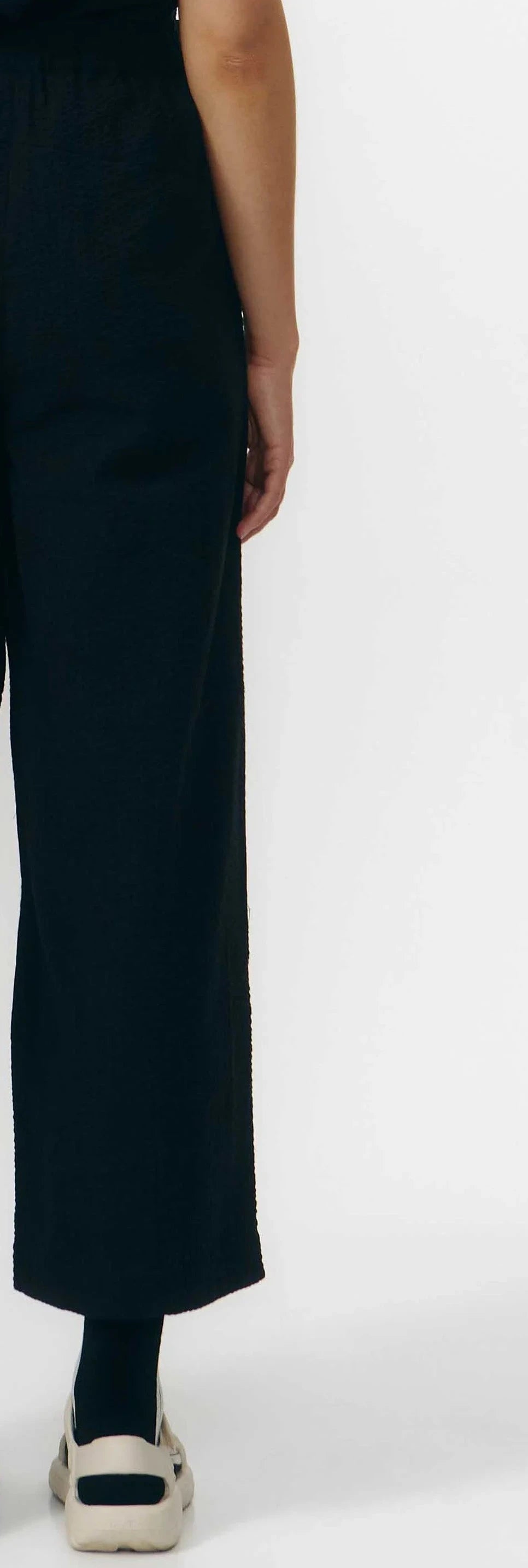Pantalón de corte culotte en color negro con pernera ancha y corta, talle alto con cintura elástica y bolsillos laterales, fabricado en algodón orgánico.