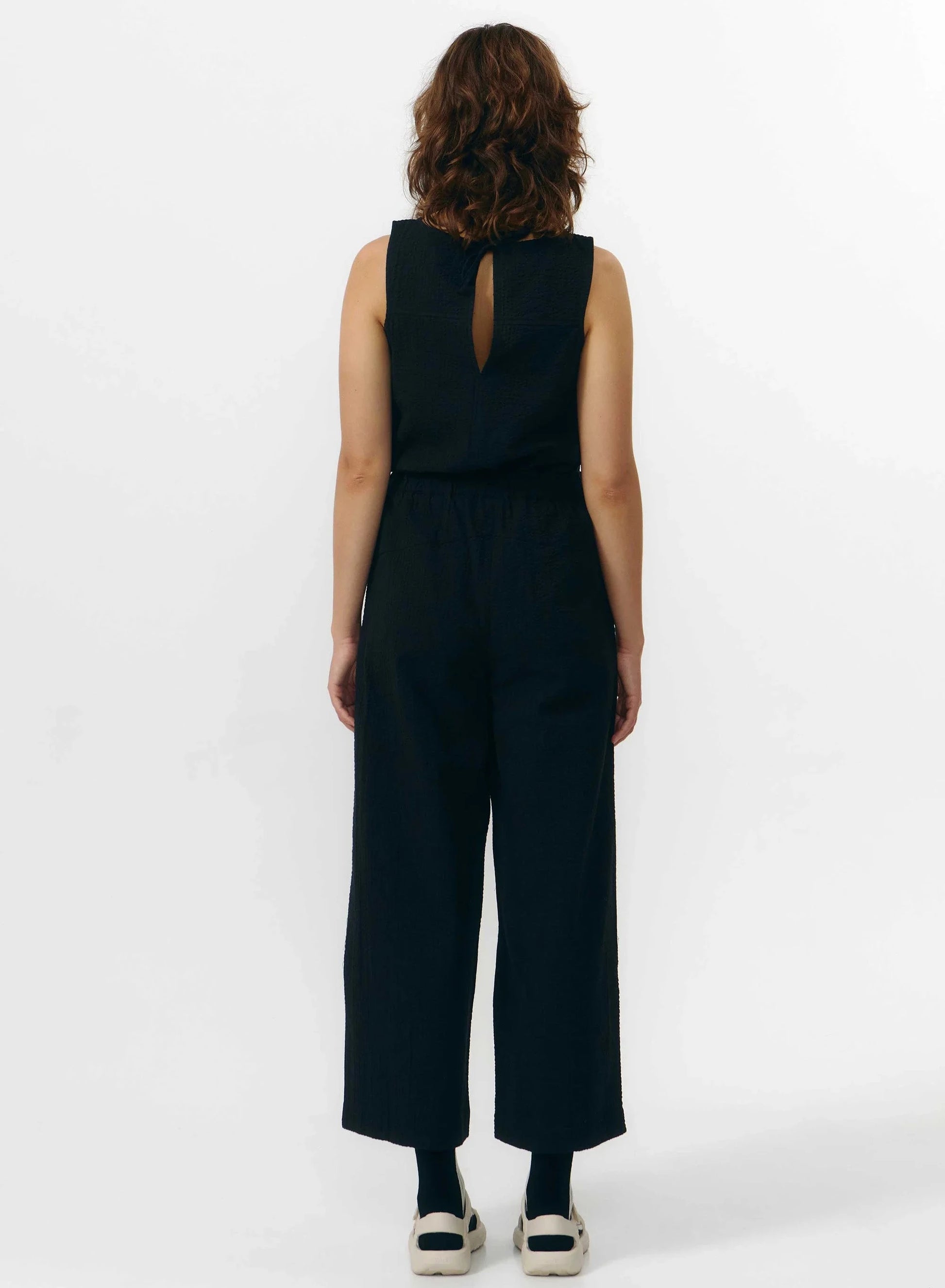 Pantalón de corte culotte en color negro con pernera ancha y corta, talle alto con cintura elástica y bolsillos laterales, fabricado en algodón orgánico.