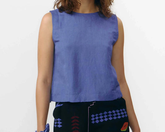 Top sin mangas de color azul medio con cuello redondo y cierre de botones naturales, con diseño reversible que permite llevar los botones en la parte frontal o trasera.