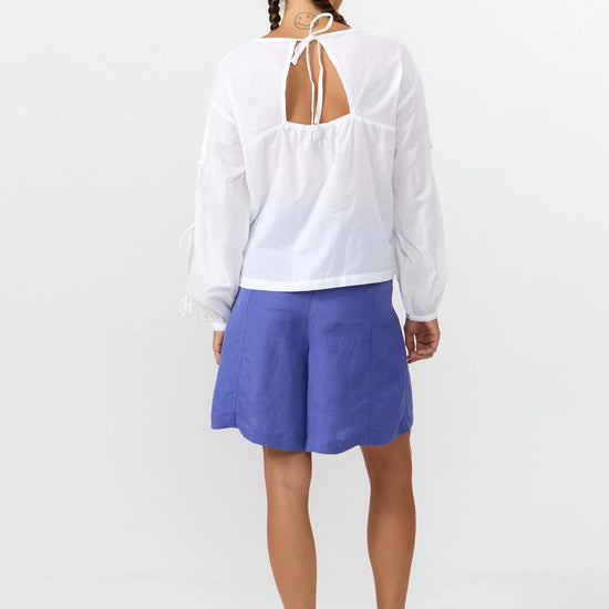 Blusa de manga larga en color blanco con cuello redondo, cierre trasero y mangas con lazos.