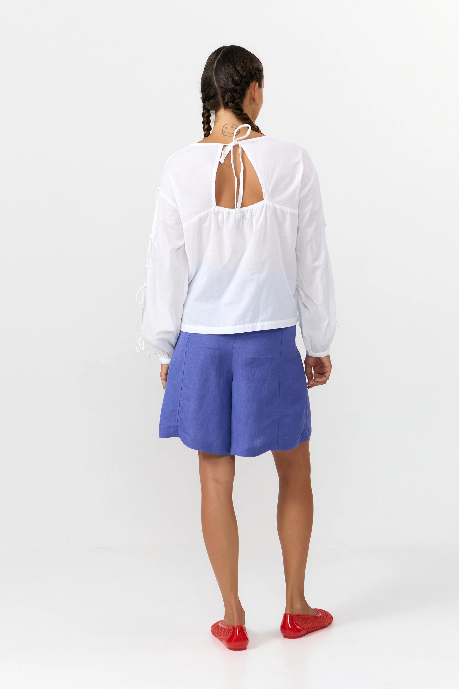 Blusa de manga larga en color blanco con cuello redondo, cierre trasero y mangas con lazos.