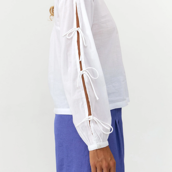 Blusa de manga larga en color blanco con cuello redondo, cierre trasero y mangas con lazos.