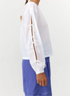 Blusa de manga larga en color blanco con cuello redondo, cierre trasero y mangas con lazos.