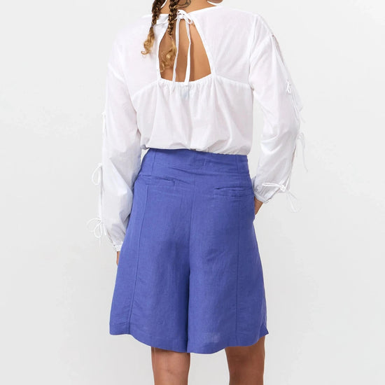 Blusa de manga larga en color blanco con cuello redondo, cierre trasero y mangas con lazos.