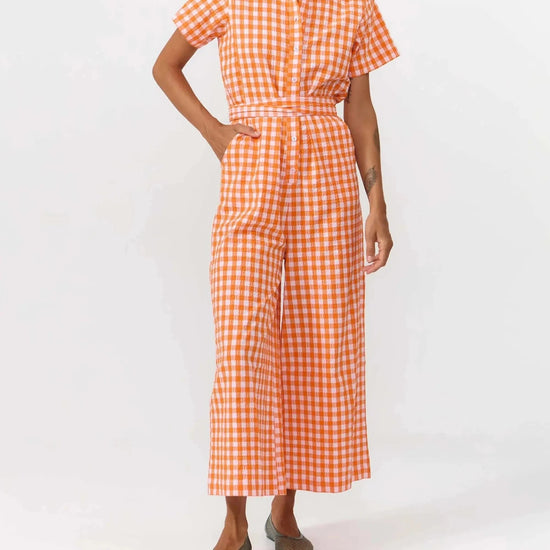 Mono largo de manga corta con estampado de cuadros en color naranja y blanco, cuello camisero, botones de corozo y cinturón ajustable de la marca Suite13 Lab.
