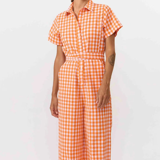 Mono largo de manga corta con estampado de cuadros en color naranja y blanco, cuello camisero, botones de corozo y cinturón ajustable de la marca Suite13 Lab.