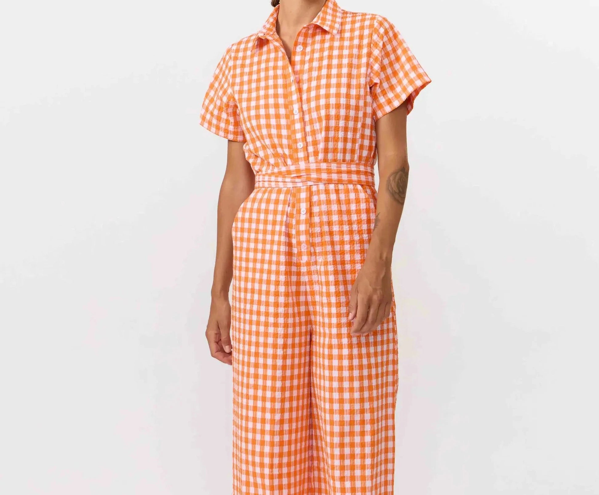 Mono largo de manga corta con estampado de cuadros en color naranja y blanco, cuello camisero, botones de corozo y cinturón ajustable de la marca Suite13 Lab.