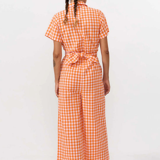 Mono largo de manga corta con estampado de cuadros en color naranja y blanco, cuello camisero, botones de corozo y cinturón ajustable de la marca Suite13 Lab.