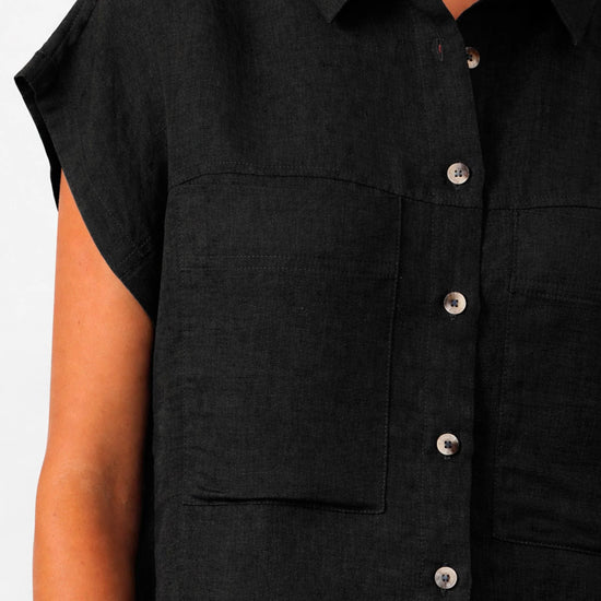 Camisa de manga corta en color negro con caída fluida, confeccionada en mezcla de lino y viscosa sostenible, con cuello clásico y botones frontales de tono natural.