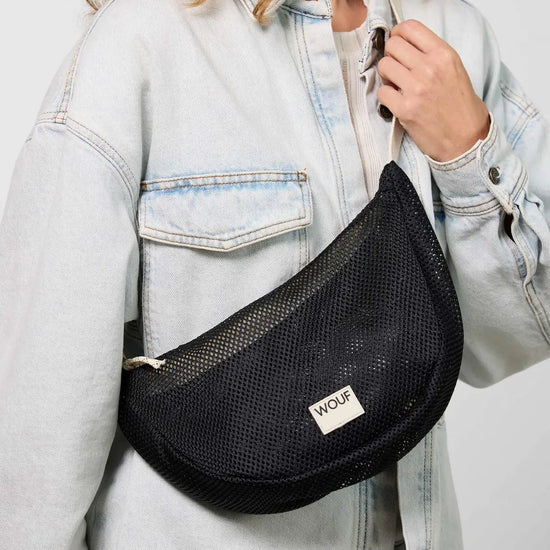 Bolso bandolera de color negro puro, de diseño estructurado con correa cruzada ajustable de algodón, cremallera superior y etiqueta de silicona, modelo Onyx de Wouf.