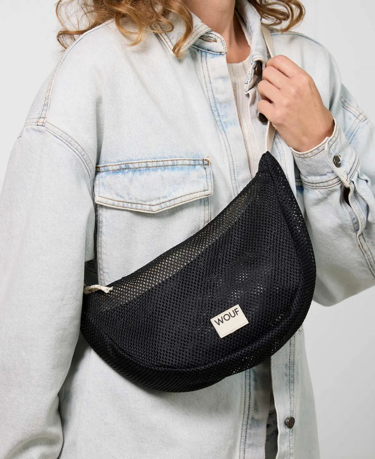 Bolso bandolera de color negro puro, de diseño estructurado con correa cruzada ajustable de algodón, cremallera superior y etiqueta de silicona, modelo Onyx de Wouf.
